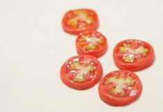 four tomatoes with yellow stuff on them sitting on a white surface