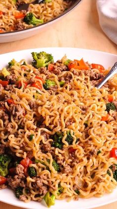 two plates filled with noodles, meat and vegetables