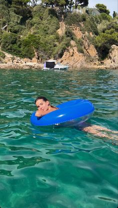 a woman floating on top of a blue raft in the ocean