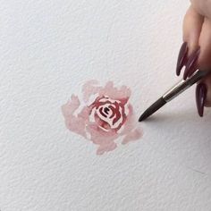 someone is painting a flower with watercolors on paper