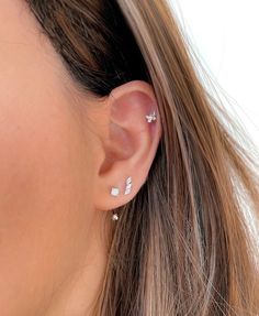 a close up of a woman's ear with three small diamond studs on it