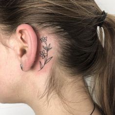 a woman's behind the ear has a small flower tattoo on her left side