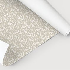 a roll of white paper on top of a beige and white wallpaper with an abstract design