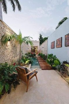 a patio with a chair and water feature in the back yard, surrounded by tropical plants