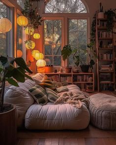 a living room filled with lots of furniture and windows covered in hanging lights next to a bookshelf