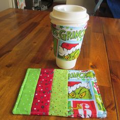 a coffee cup sitting on top of a wooden table next to a green and red napkin