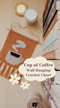 cup of coffee wall hanging crochet chart on table next to yarn and candles