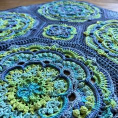 there is a crocheted blue and green blanket on the floor