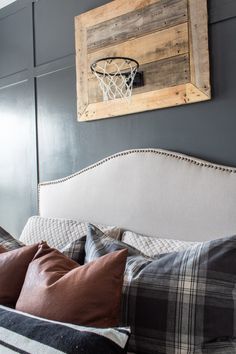 a bed with pillows and a basketball hoop mounted on the wall above it's headboard