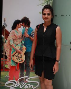 a woman standing in front of a poster with a guitar on it's side