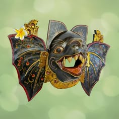 a mask with an open mouth is hanging from a string on a green boke background