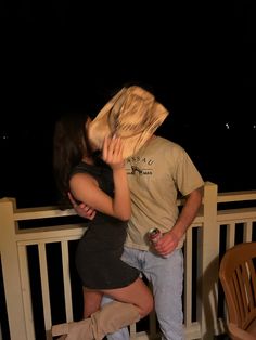 a man kissing a woman on the cheek while standing next to a wooden bench at night