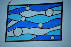 a stained glass window hanging from a chain on a wall with blue sky in the background