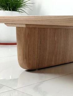 a wooden bench sitting on top of a tiled floor next to a potted plant