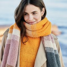 a woman standing on the beach wearing a scarf