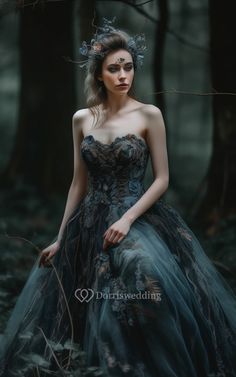 a woman in a blue dress standing in the woods with her hands on her hips