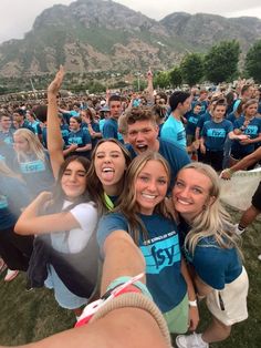 a group of young people taking a selfie in front of a large mountain range