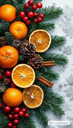 an arrangement of oranges and pine cones on a white surface with evergreen leaves, berries, cinnamon sticks, fir cones, and red berries