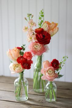 three vases filled with flowers on top of a wooden table