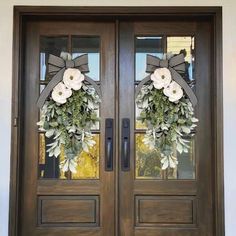 the front door is decorated with wreaths and flowers on it's glass panels