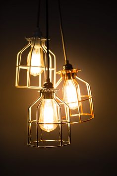 three light bulbs hanging from a wire caged chandelier over a dark background