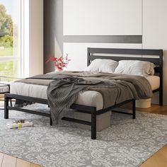 a bedroom with a bed, nightstands and rug in front of a large window