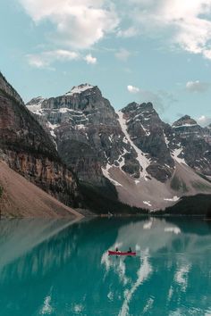 a person in a kayak on a lake surrounded by mountains