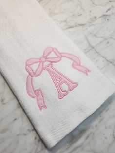 a white towel with a pink bow on it sitting on top of a marble counter