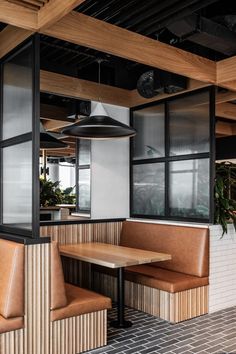 the inside of a restaurant with wooden booths and leather seats, plants in pots on the wall