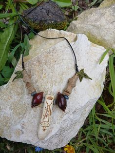 a necklace with two beads on it sitting on top of a rock in the grass