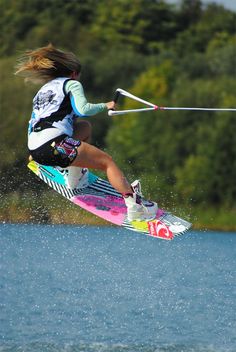 a person on skis in the air above water with trees in the back ground