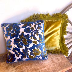 two blue and green pillows on a wooden bench