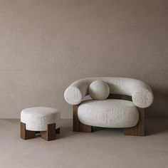 a white chair and ottoman sitting next to each other on a cement floor in front of a gray wall