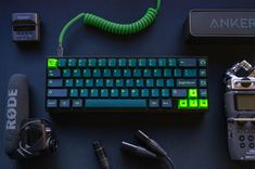 a keyboard, headphones, and other electronic equipment are on a table with the word anker written in green