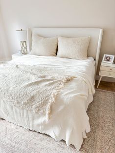 a bed with white sheets and pillows on top of it