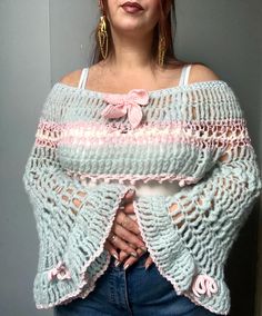 a woman wearing a blue crochet shawl with pink flowers on the side