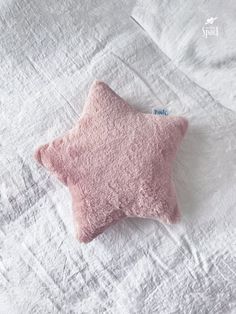 a pink star shaped pillow sitting on top of a bed