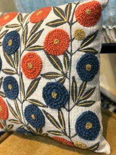 an embroidered pillow with blue and orange flowers on it