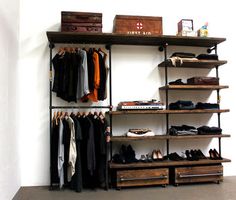 an organized closet with clothes, shoes and suitcases hanging on the wall next to it