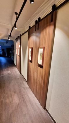 an empty hallway with wood paneling and pictures on the wall next to each other