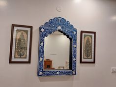 a blue and white mirror sitting on top of a wall next to two framed pictures