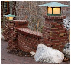 a brick wall with two lamps on top and a rock in the middle next to it