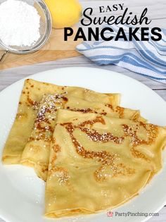 two pancakes on a white plate with powdered sugar