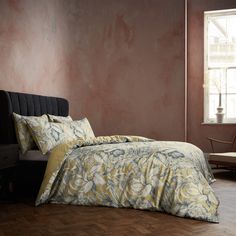 a bed sitting next to a window in a bedroom on top of a hard wood floor