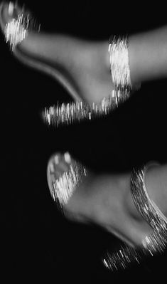 two pairs of feet with shiny silver paint on their toes and toenails, in black and white