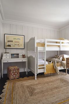 a bedroom with two bunk beds and a rug on the floor in front of it