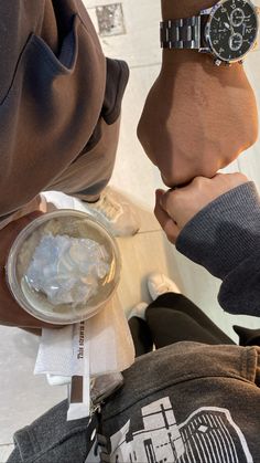 two people holding hands over an ice cube with a watch on it's wrist