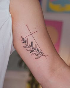 a woman's arm with a cross and leaves tattoo on the left side of her arm