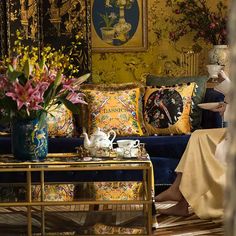 a woman sitting on top of a couch next to a table with flowers in vases