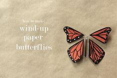 two orange butterflies sitting next to each other on top of a piece of paper with the words wind up paper butterflies